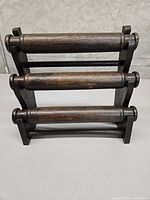 Front view of dark wood rack showing three horizontal dowel pins