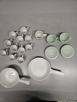 Group view of all items: two Corning Ware pans, white espresso cups, green cups with saucers, Niagara Falls mug