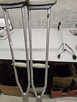 Pair of adjustable aluminum crutches leaning against table