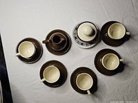 Overhead view of five espresso cups on saucers, creamer and sugar bowl on decorative plate