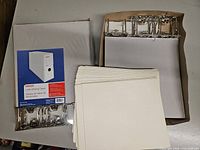 Open boxes showing Staples letter binding cases, metal ring mechanisms, and stack of folder covers