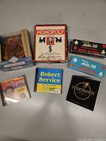 Group shot of all items: travel Monopoly, two poker chip sets, Greek Computer puzzle, three CDs
