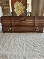 Front view of wooden jewelry box showing brass-tone latches and curved front