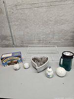 All items grouped on table: boxed card shuffler, wire rack, heart planter, green flashlight, three visible pomanders