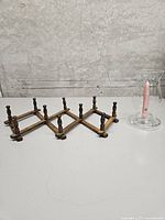 Wooden accordion coat rack and glass hurricane candle holder side by side
