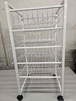 Side view of white metal cart showing five wire baskets and casters