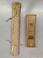 Closed fabric roll tied and wooden slide-lid box standing