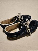 Side view of both shoes showing suede material, stitching, laces
