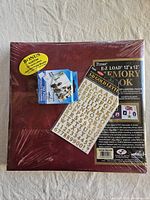 Front view of shrink-wrapped burgundy scrapbook album with sticker sheet and photo squares pack
