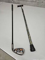 Mizuno 7 iron and adjustable cane side by side on table