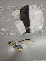 Bag containing white pleater tape, hook-and-loop strip and black banding alongside electric scissors cord