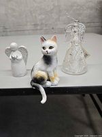 All three items: tri-colour cat, white angel figurine, clear glass angel ornament