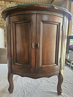 Front view of barrel end table showing two paneled doors and cabriole legs