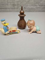 Overview of all three main items: Donald Duck toy, crawling baby toy, wooden bottle with vial inside