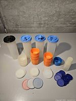Full lot showing four tall containers, stacks of tumblers, jigger cups, and lids