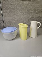 Three items: Tupperware lettuce keeper, yellow container, white ceramic pitcher