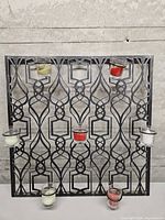 Front view of metal holder showing seven votive positions with candles