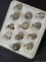 All 14 silver-tone rhinestone rings in display tray