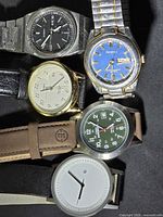 Five wristwatches arranged together showing variety of dials, cases and straps