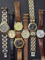 Seven watches laid out side by side on dark background