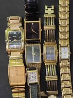 Front view of all seven gold-tone tank style wristwatches