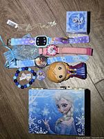 Full lot overview on wood floor showing watches, figurine, bracelet, necklaces, music box and storage box
