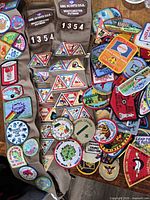 Overview of three sashes and loose pile of assorted Girl Scout patches