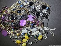 Overall view of tangled assortment of necklaces showing variety of beads and chains
