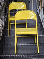 Front view of both yellow metal folding chairs on staircase
