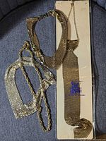 Group shot showing necktie in packaging, choker necklace and mesh purse