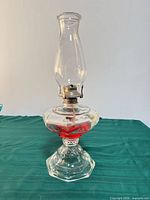 Full view of oil lamp showing chimney, burner, glass font and hexagonal base