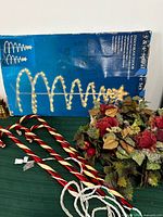 Box showing Bright Tidings spiral trees, connected candy cane lights, cords, portion of wreath