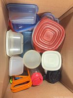 Top view inside box showing assortment of square and rectangular plastic containers with lids plus travel mug and graters