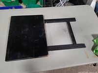 Tray table folded flat showing black wood top and collapsed legs