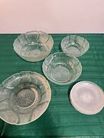 Group shot of all glass pieces: large bowl, two medium bowls, shallow dish, stack of six small plates