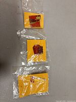 All three Coca-Cola enamel pins sealed on yellow cards