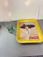 Green contour glass beside yellow-border advertising tray