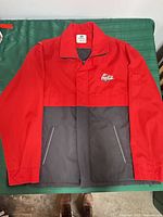 Front view of red and black Coca-Cola jacket showing zipper, pockets, and logo