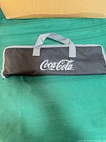 Closed black zippered carrying case with Coca-Cola logo