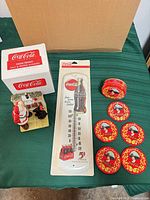 Lot overview showing thermometer, coasters, tin, and shakers with original box