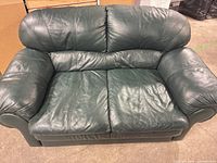 Front view of green leather loveseat showing overall design and condition