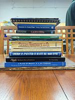 Stack of books showing identifiable spines including Cars: 1950s, Cadillac, Mack, The Great Luxury Liners, Sears Roebuck & Co., American Painted Furniture