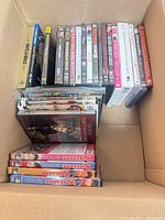 Assorted DVDs stacked inside shipping box showing quantity and spines