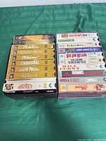 Stacks of VHS tapes including Rodgers & Hammerstein gold cases and assorted action/western titles