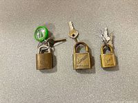 Front view of three brass padlocks with their keys attached