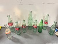 Group shot of all nine Coca-Cola glass bottles arranged in a row