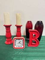 Group shot showing two ombré vases, two red candle holders with ivory candles, red letter B decor, red square alarm clock