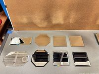 Eight small beveled glass mirror tiles in various shapes laid out for size and condition reference