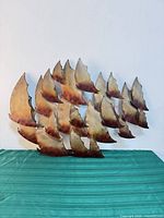 Front view of metal abstract wall sculpture showing sail-shaped panels and patina finish