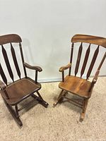 Two small wooden rocking chairs, dark and light finish